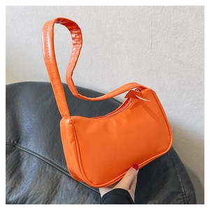 Close-up of vibrant orange semi-circle underarm bag in smooth vegan leather