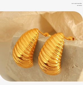 Detailed close-up of 18K gold-plated stainless steel earrings with spiral texture on stone