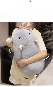 Close-up of a large grey plush mouse toy held in a cozy home setting as a soft pillow