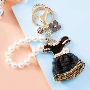 Detailed view of pearl keychain with black dress charm and gold metal ring hardware