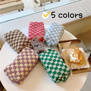 Detailed view of 5 colors knitted checkerboard makeup bags arranged on a white table