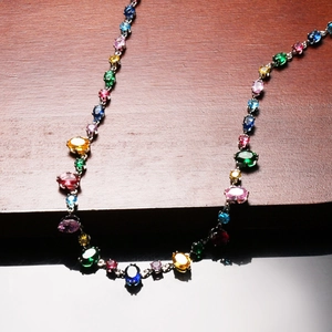 Detailed view of oval cut multi-color crystal necklace on wood and mirror surface