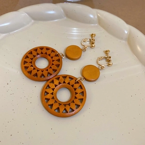 Detailed macro view of mustard yellow vintage wood hollow sun geometric clip-on earrings