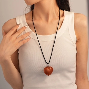 Gros plan d'un pendentif cœur en similicuir marron avec coutures fines et cordon noir