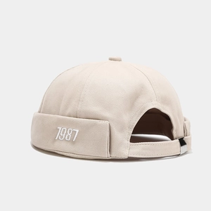 Dettaglio del berretto docker beige con ricamo 1987 e cinturino regolabile in metallo