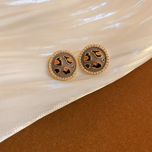 Macro shot of vintage round leopard print studs with pearls on silk fabric background
