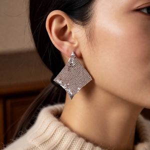 Gros plan de boucles d'oreilles géométriques en maille argentée sur un mannequin