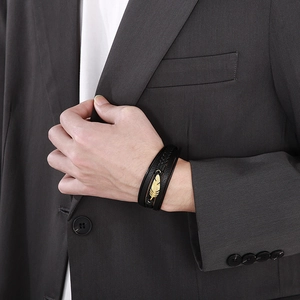 Close-up of men's multilayer braided leather bracelet with golden feather charm on wrist