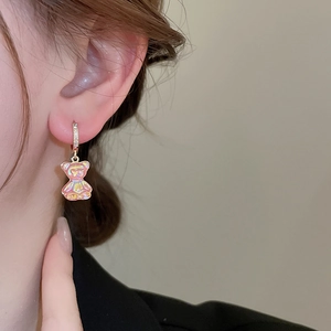 Gros plan d'une boucle d'oreille ours en résine rose irisée avec zircon doré sur modèle