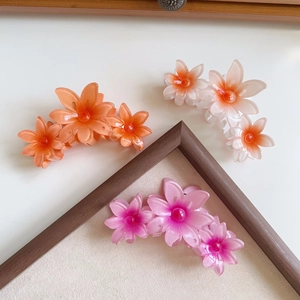 Detailed view of large matte flower hair claws in pink and orange gradient resin