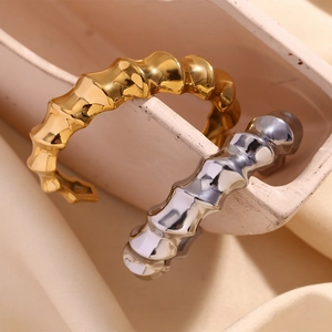 Detail of twisted bamboo knot open cuff bracelets in polished gold and silver finishes