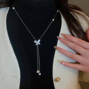 Macro detail of butterfly pendant with pavé zircons and elegant pearl charms