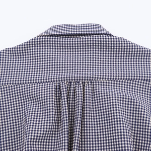 Détail du col rabattu et du pli dorsal sur la chemise à carreaux bleue et blanche