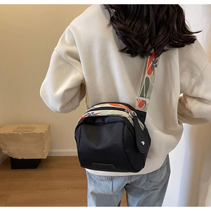 Dettaglio della borsa a tracolla in nylon nero con un'ampia tracolla a motivi colorati