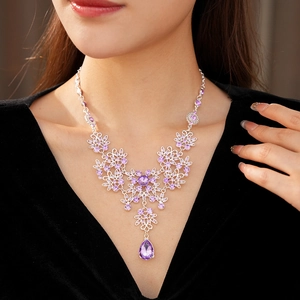 Close-up of vintage flower pendant necklace with purple crystals on a female neck