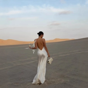 Elegant white backless satin maxi dress with cowl neck and thin straps in desert setting