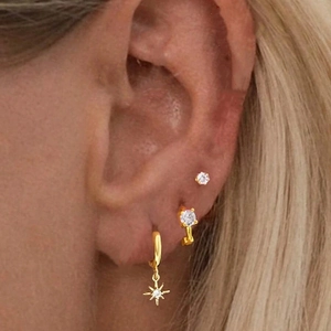 Close-up of gold starburst hoop earrings set with rhinestones worn on ear