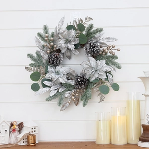 Frosted Christmas wreath with silver flowers and pine cones on a white wooden wall