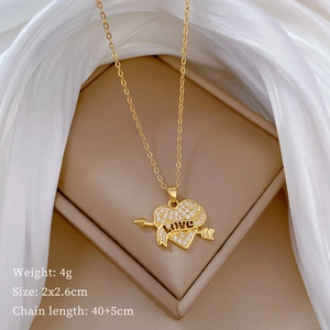 Detail of gold heart pendant with crystal arrow and LOVE engraving on white silk