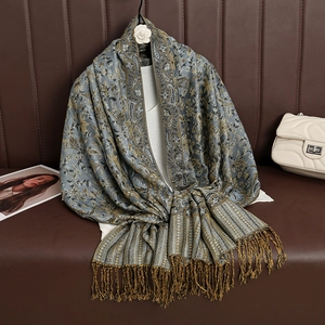 Detail of blue-grey paisley cashmere-feel scarf with gold fringe on a leather backdrop