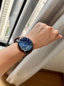 Close-up of a blue dial quartz watch with brown leather strap worn on a wrist