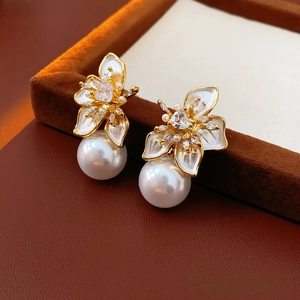 Close-up of gold flower petal earrings with large white pearl and cubic zirconia details