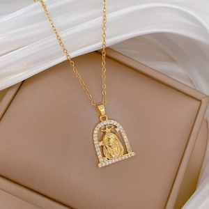 Détail d'un collier en titane doré avec pendentif arche serti de diamants et relief de figure