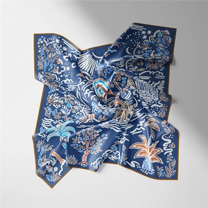 Detail of blue silk scarf featuring brown botanical prints and elegant silk texture