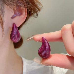 Detailed macro view of purple teardrop resin earring with marble texture on a model