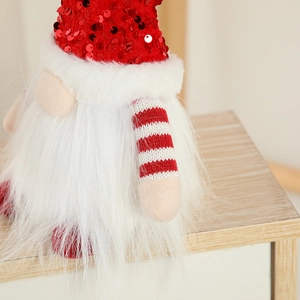 Christmas gnome doll with red sequin hat and white faux fur beard on wood surface