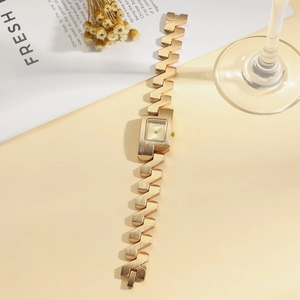 Detail of gold rectangular fashion watch with geometric link chain on magazine