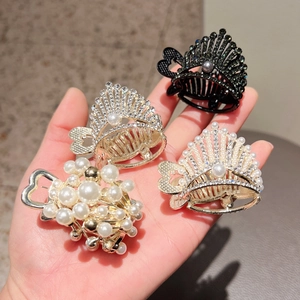 Detail of elegant hair claw clips with pearls and rhinestones held by hand