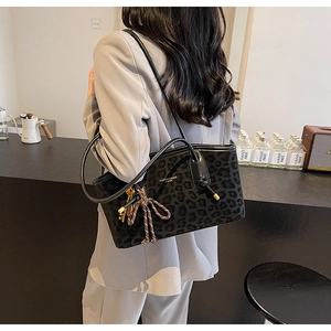 Détail macro du sac cabas léopard avec bandoulières en cuir noir et pendentifs tendance