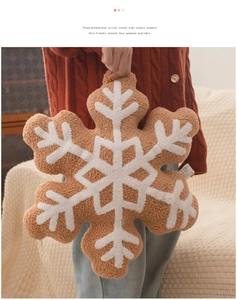 Detailed view of brown and white snowflake plush pillow held by a person