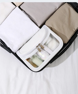 White PVC makeup bag with transparent window and zipper inside a suitcase for travel