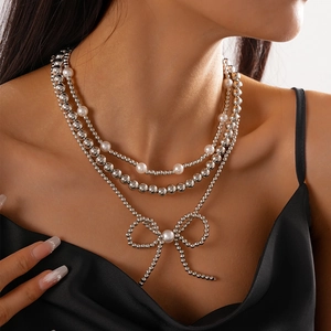 Close-up of triple-layered silver beaded necklace with faux pearl bow pendant on model