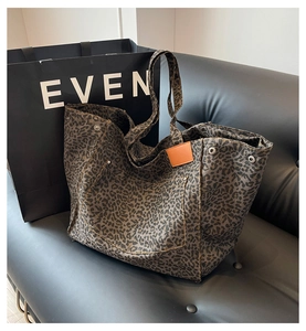 Detail of leopard print canvas tote bag featuring front pocket and metallic rivets