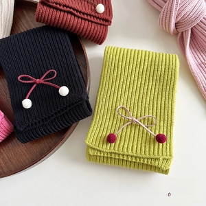 Detail of ribbed knit scarves in multiple colors with cute bow ties and pompom accents
