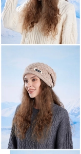 Close-up of beige chunky knit beanie featuring hollow patterns and brand logo label