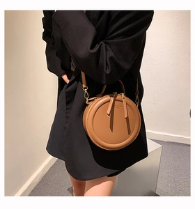 Dettaglio di borsa a tracolla rotonda vintage caramello con finiture in oro e zip