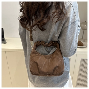 Braune Plissee-Halbmondtasche als Schultertasche am Model zur Textur- und Größenanzeige