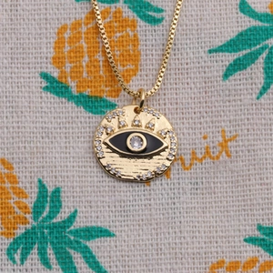 Détail du pendentif œil maléfique plaqué or avec zircons et émail noir sur chaîne box