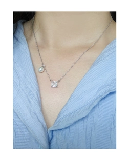 Detailed close-up of a square zircon and white pearl pendant on a silver S925 necklace