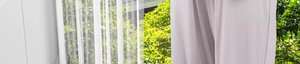 Detail of white sheer curtain and light grey blackout fabric in natural window lighting