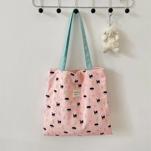 Detail of pink bubble fabric tote bag with blue straps and cute embroidered bear pattern