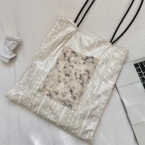 Detail of floral lace canvas tote bag with slim black straps on minimalist desk setup