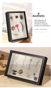 Detail of a black wooden shadow box frame featuring dried flowers and botanical specimens