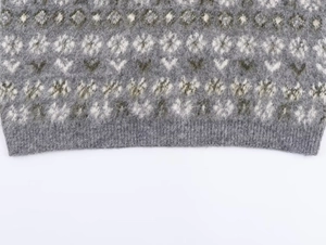 Detail of Fair Isle knit sweater showing snowflake pattern and ribbed hem texture