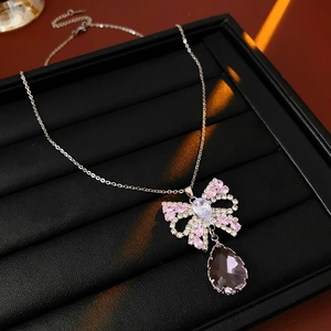 Close-up of bow necklace featuring pink and white crystals with a water drop gemstone