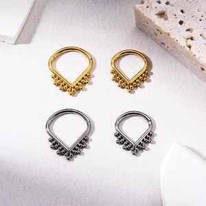 Detailed view of V-shaped titanium septum rings in gold and silver finishes